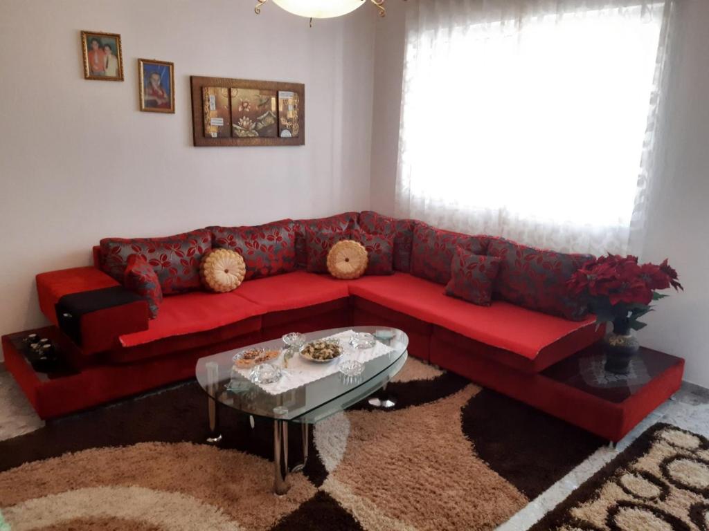 a red couch in a living room with a table at Armand's home in Korçë
