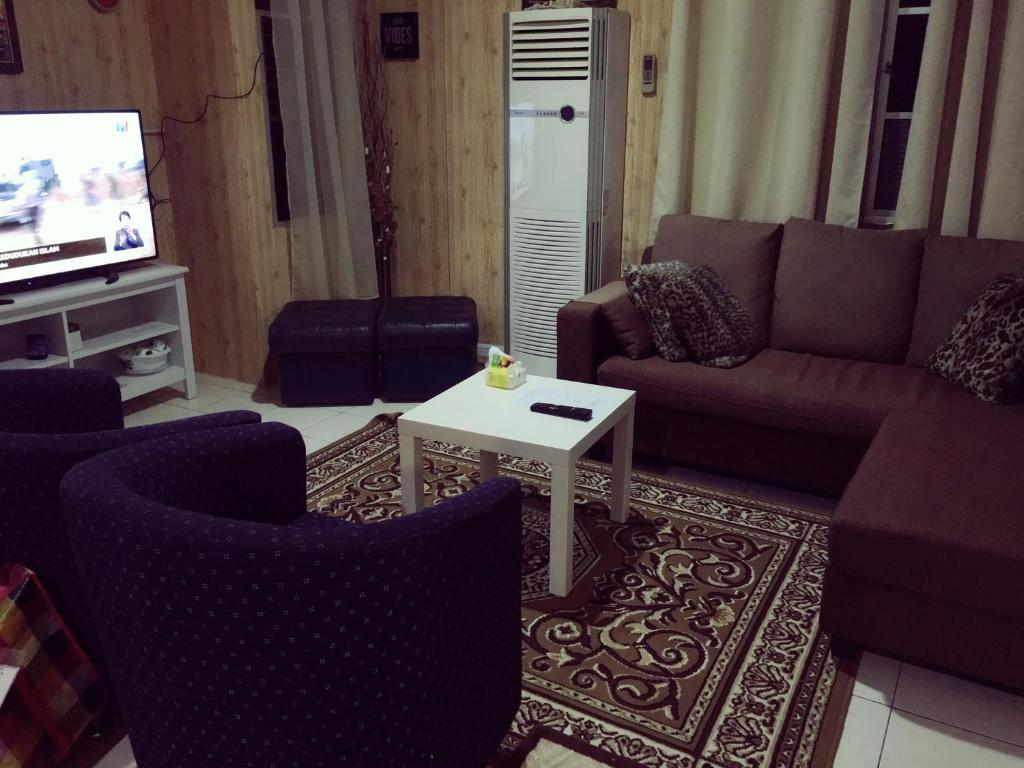 a living room with a couch and a table and a tv at IRWAN FAIZ GUEST & HOMESTAY in Kampung Gita