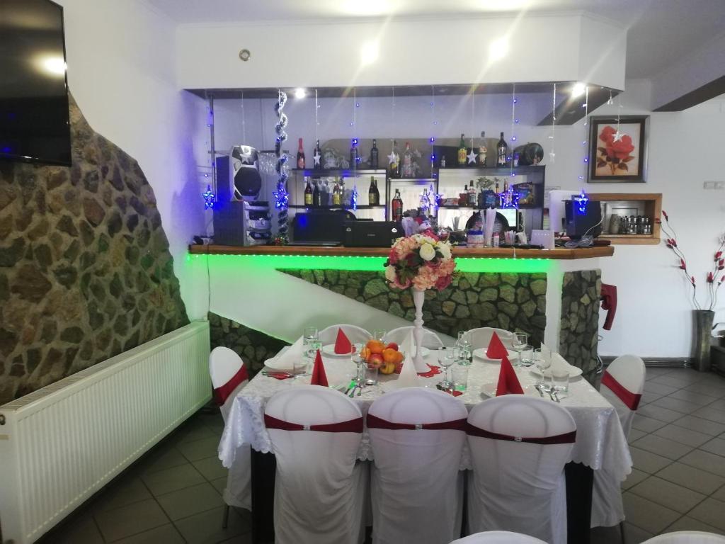 a dining room with a table with white chairs and a bar at Restaurant Vi La Maria in Baia de Fier