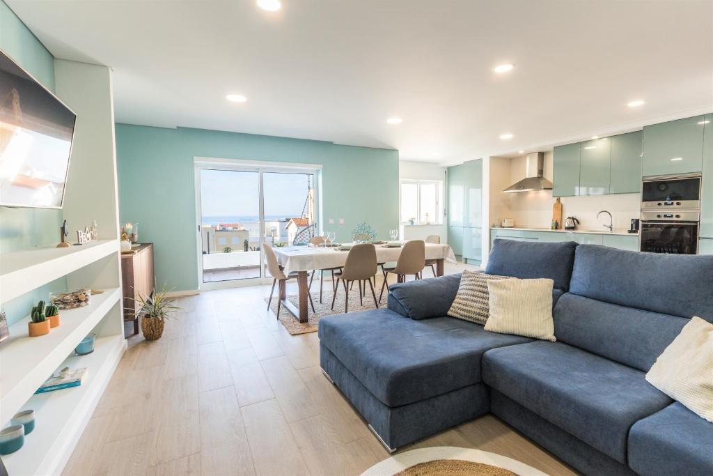 ein Wohnzimmer mit einem blauen Sofa und einer Küche in der Unterkunft COAST WAY BEACH HOUSE in Moledo