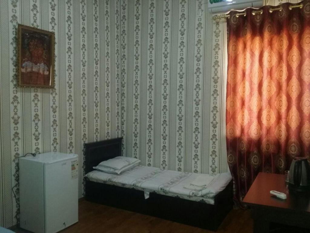 a small bed in a corner of a room at Отель RATMINA- MUINAK in Mŭynoq