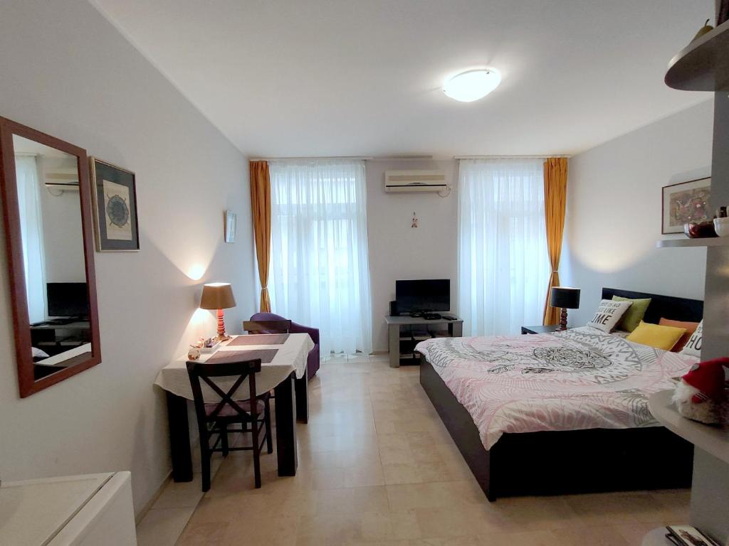a bedroom with a bed and a table and a desk at City Center Lovely Studio Apartment in Belgrade