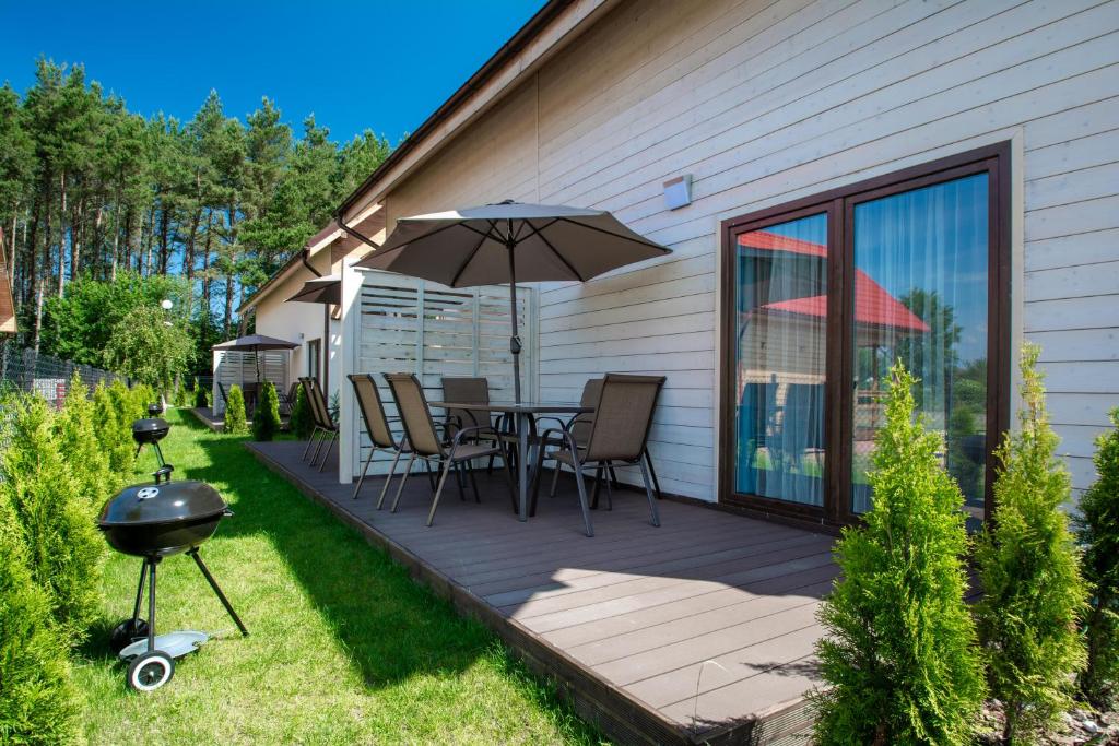 a patio with a table with an umbrella and a grill at Domki Apartamentowe Kierunek Rozewie in Jastrzębia Góra