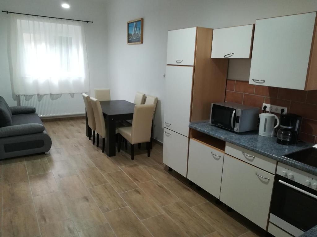 cocina y sala de estar con mesa y microondas en Sümegi Levendula Apartmanok, en Sümeg