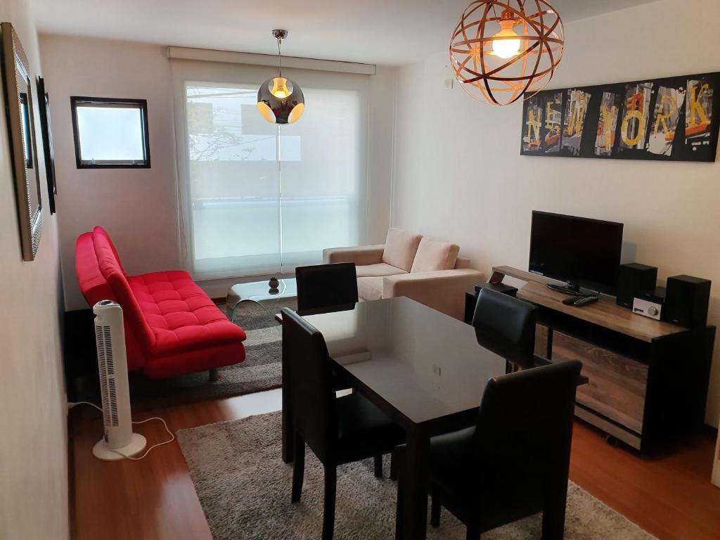 a living room with a table and a red chair at Miraflores 820 in Lima