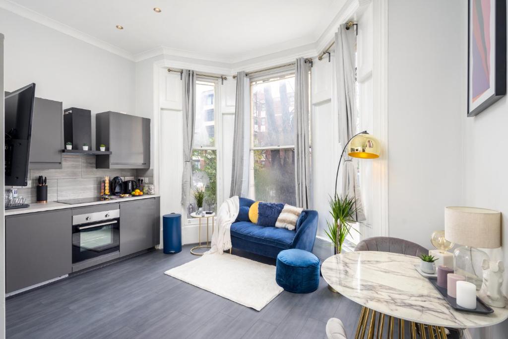 een woonkamer met een blauwe stoel en een tafel bij Kensington Modern Apartment in Londen