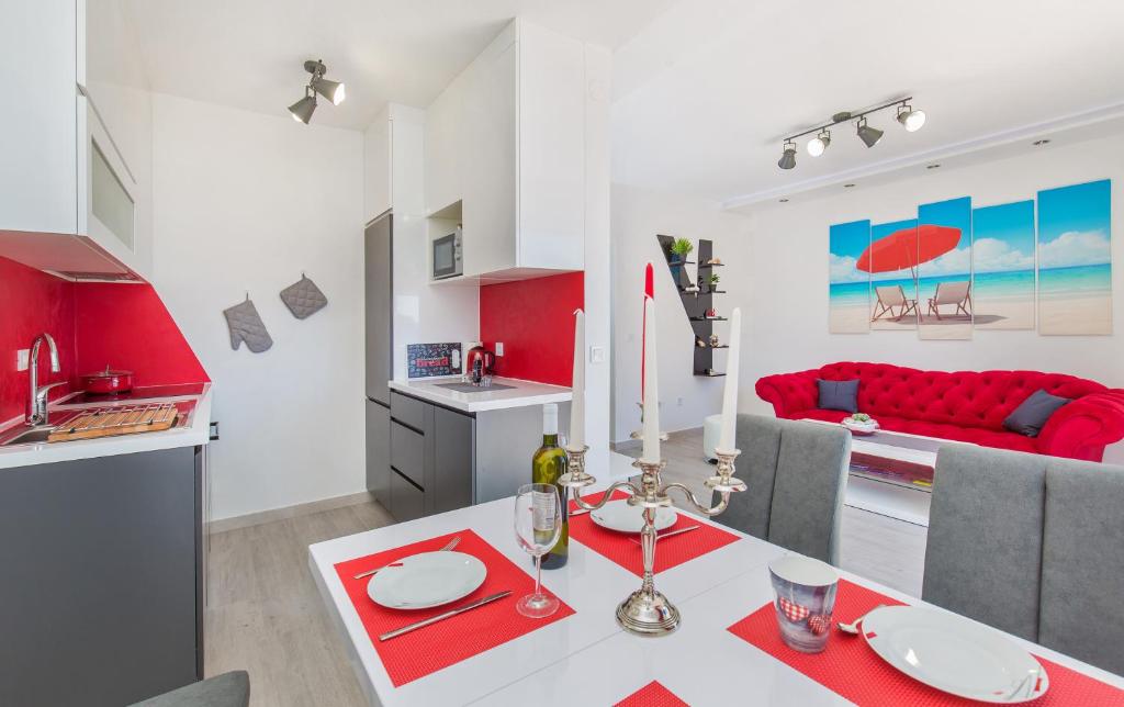 a kitchen and living room with a table and a red couch at Apartments More in Sobra