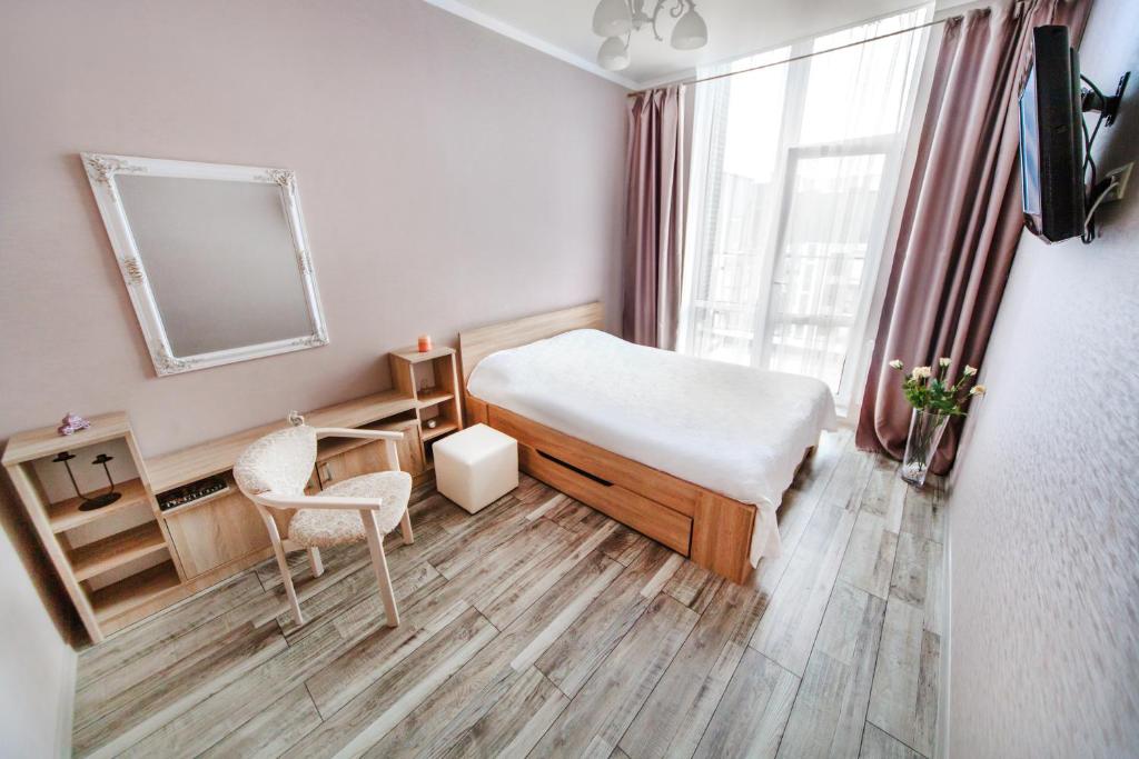 una camera con letto, sedia e specchio di Однокомнатная VIP квартира на Славянке с террасой a Vinnycja