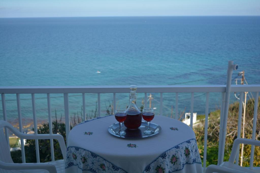 uma mesa com dois copos de vinho tinto numa varanda em FIORE ROOMS em Akrotiri