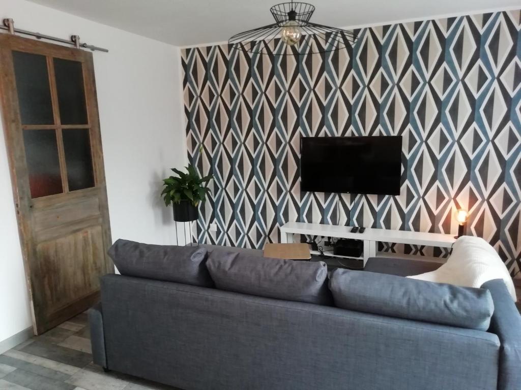 sala de estar con sofá y TV en La Petite Pause en Verlinghem