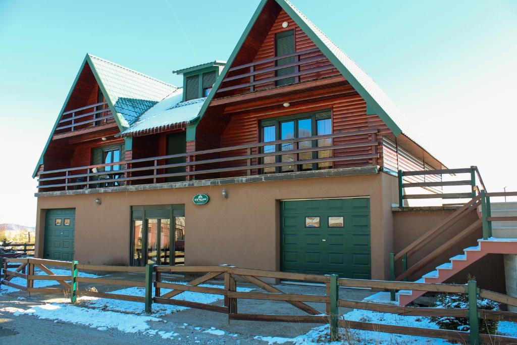 a house with a gambrel roof with green doors at Sun Village Apartments Zabljak in Žabljak