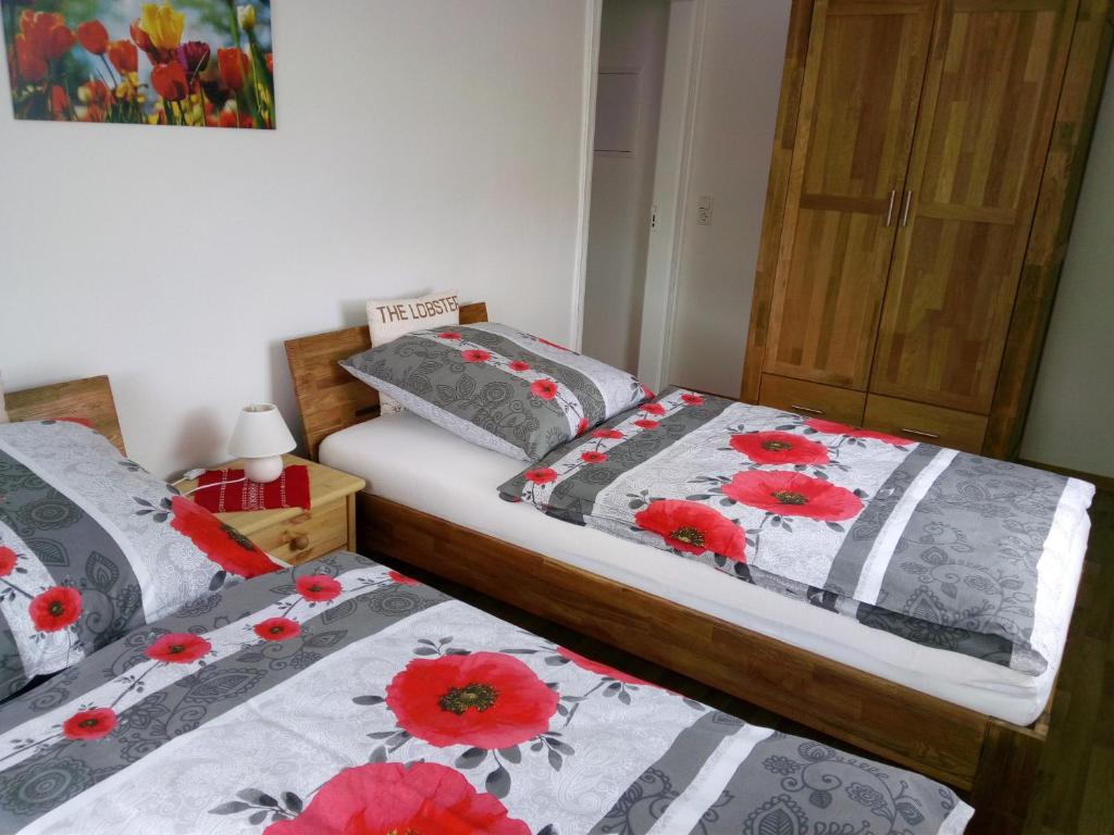 two beds in a room with red flowers on them at Ferienwohnung Familie Schneider in Neustadt in Sachsen