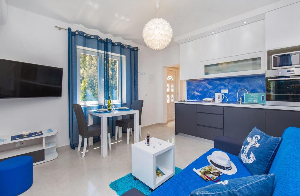 a living room with a blue couch and a kitchen at Apartments More in Sobra