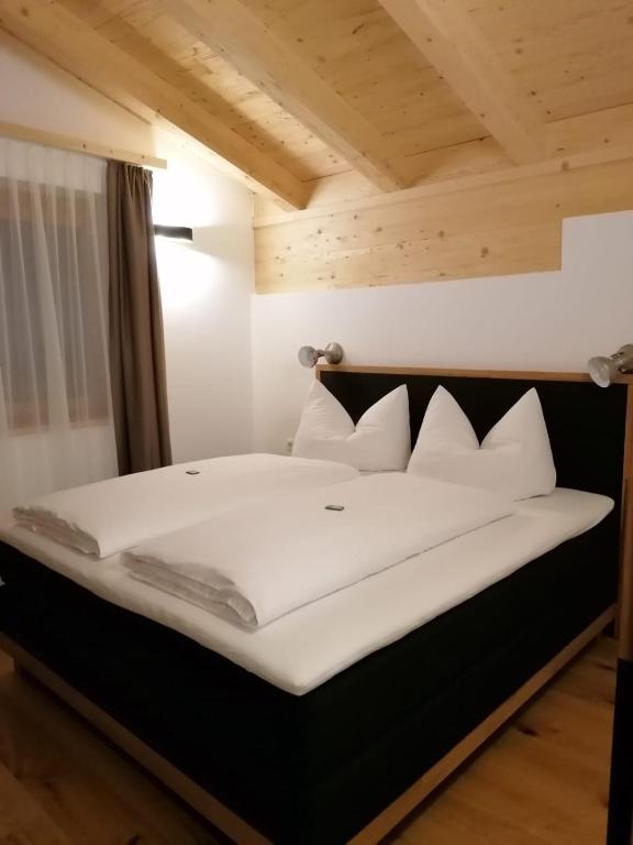 un letto con lenzuola e cuscini bianchi in una stanza di Studler Hofchalets a Oberperfuss