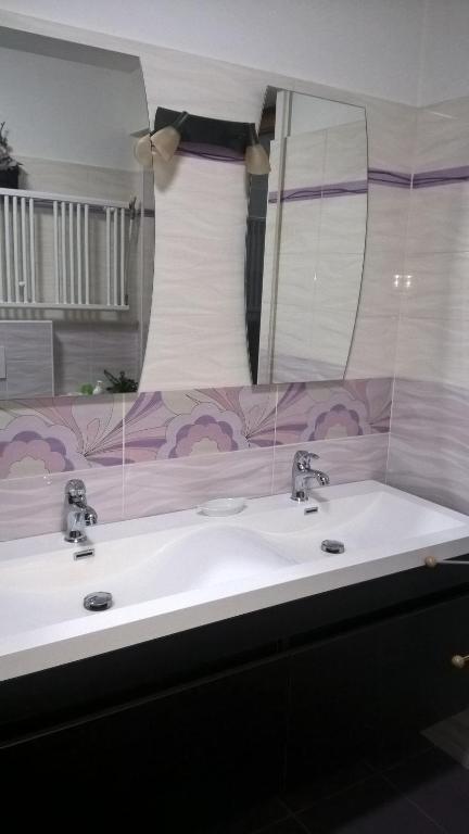 La salle de bains est pourvue de 2 lavabos et d'un grand miroir. dans l'établissement Leoni, à Santa Giustina
