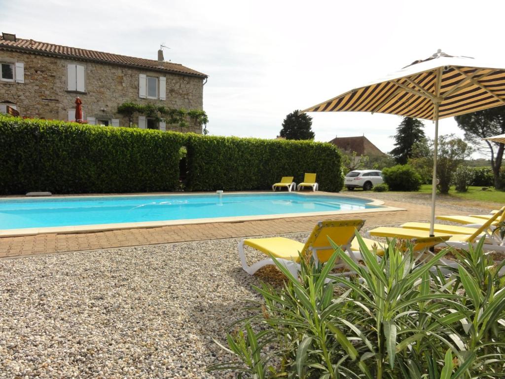 a swimming pool with chairs and an umbrella at Gîte La Jaujon in Lablachère