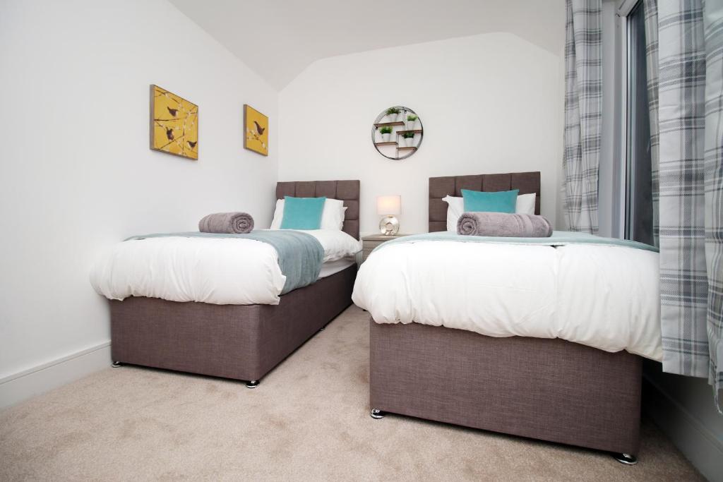 two beds sitting next to each other in a bedroom at Spacious 4BR Home Near Swansea Sleeps 8 in Swansea