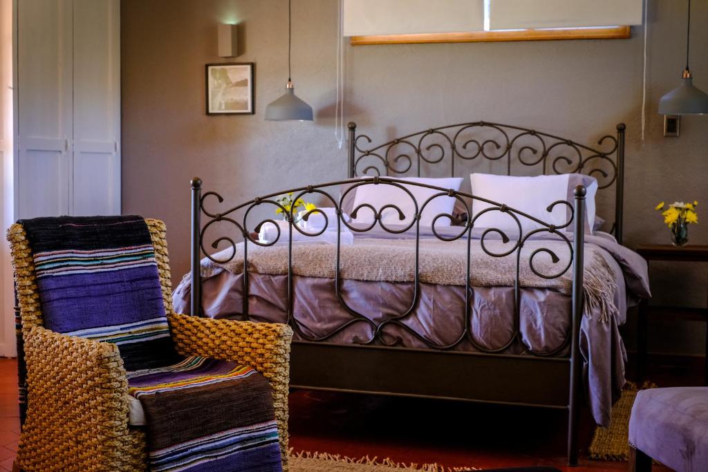 1 dormitorio con cama de metal y silla en Hacienda Bellavista, en Villa Alemana
