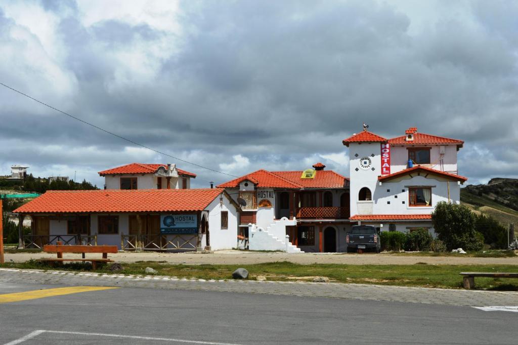 un bâtiment blanc avec un toit rouge dans une rue dans l'établissement Quilotoa Green Lake, à Quilotoa