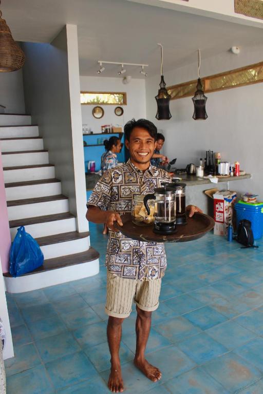 a man holding a tray with a pot on it at Serenity Luxurious Beachfront Villa & Spa with private Infinity Pool, 8 Guests in Gili Air