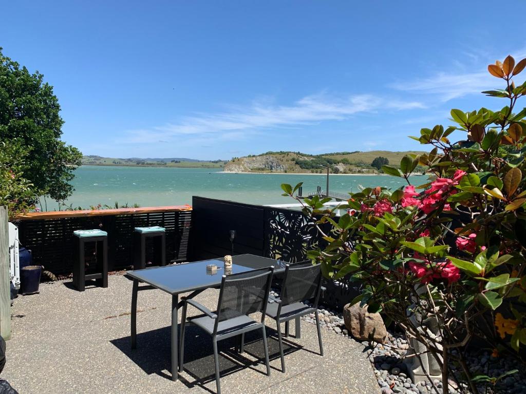 a table and chairs with a view of the water at Beach Lane Apartment in Whangarei