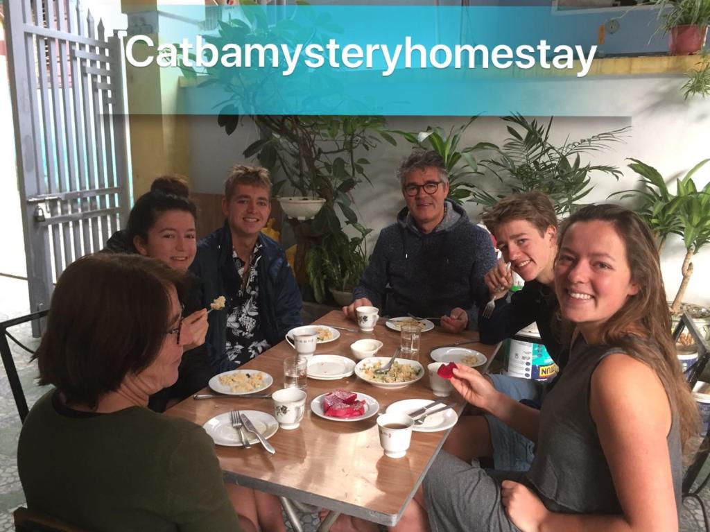 um grupo de pessoas sentadas à volta de uma mesa a comer em Cat Ba Mystery Homestay em Ilha de Cát Bà