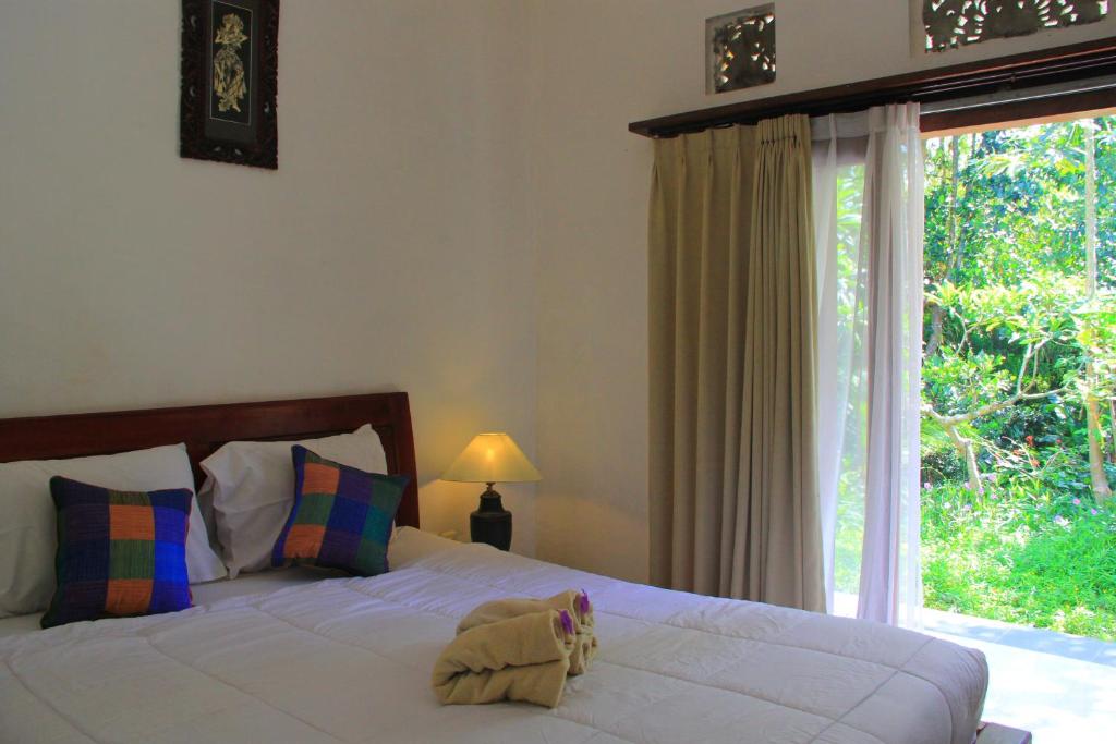 1 dormitorio con cama y ventana grande en Sila Urip Guest House, en Ubud