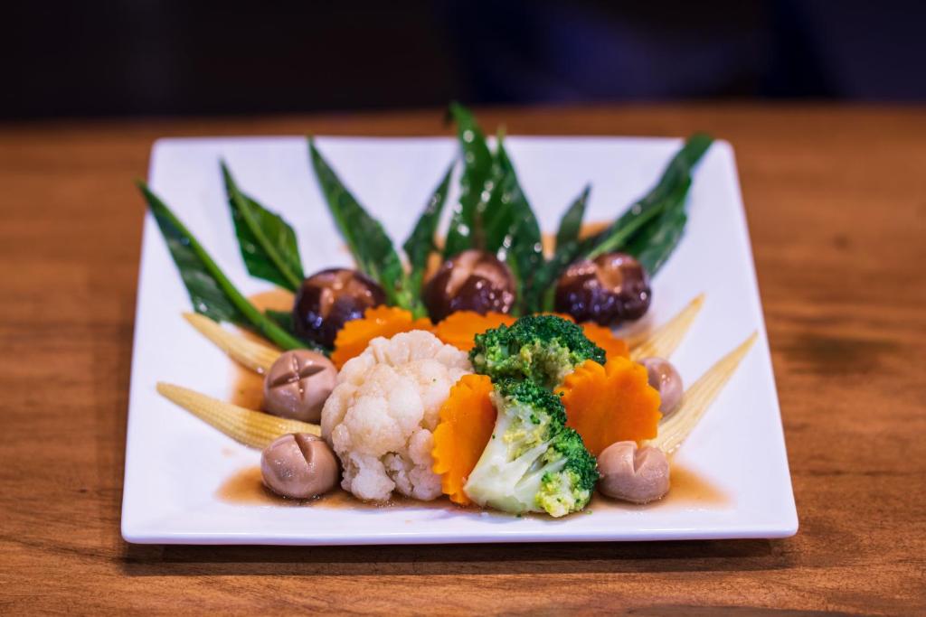 a plate of food with vegetables on a table at River Front Krabi Hotel in Krabi