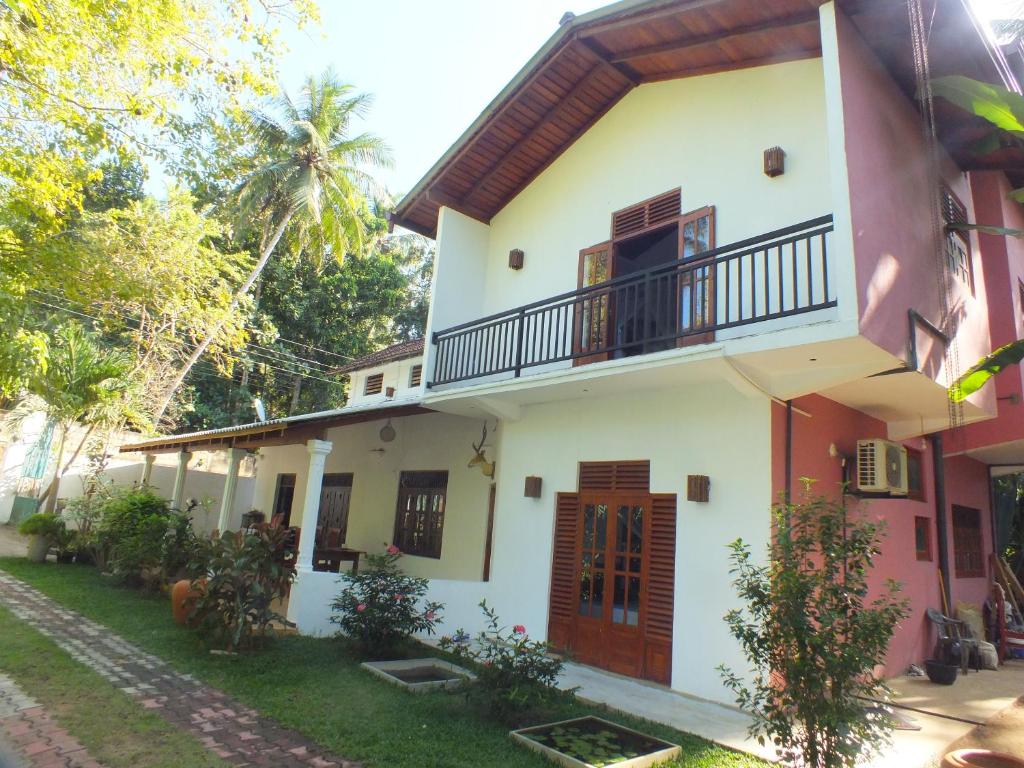 uma casa com uma varanda e um quintal em Abraham Beach House em Tangalle