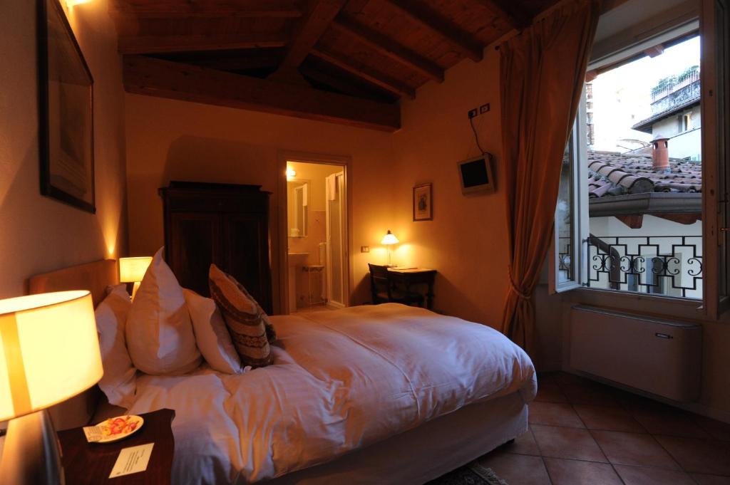 ein Schlafzimmer mit einem Bett und einem großen Fenster in der Unterkunft Albergo Orologio in Brescia