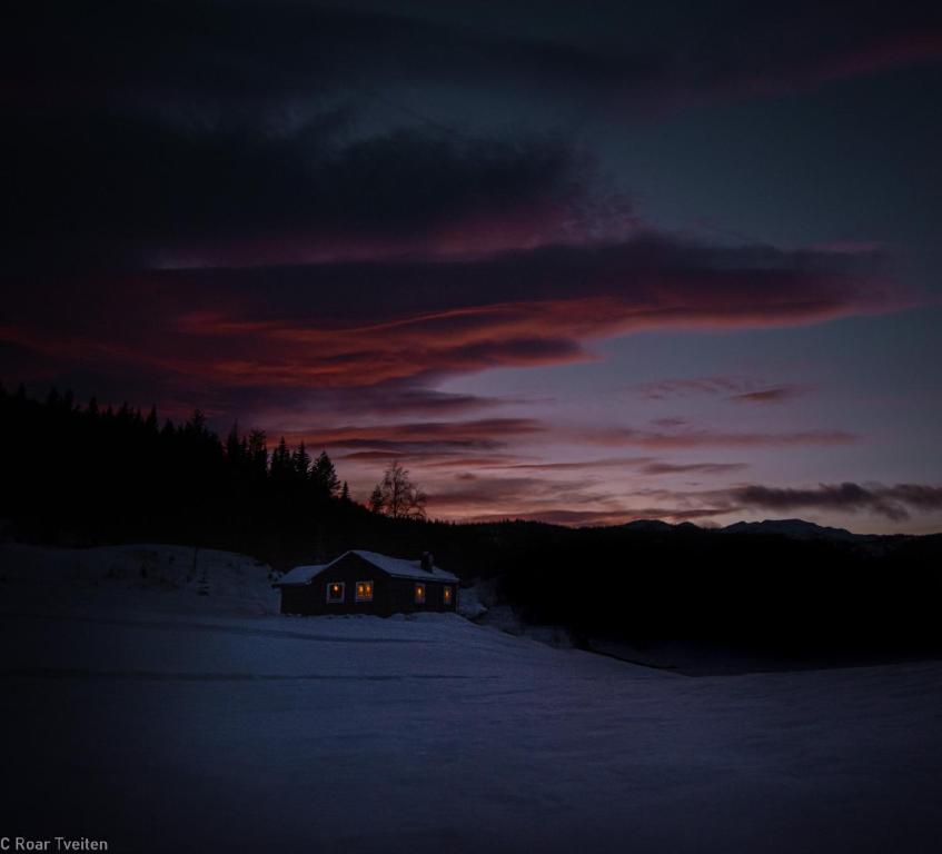 Tuddal的住宿－Tuddal Hyttegrend, GAMLESTUGU, Telemark，雪中的房子,背景是日落