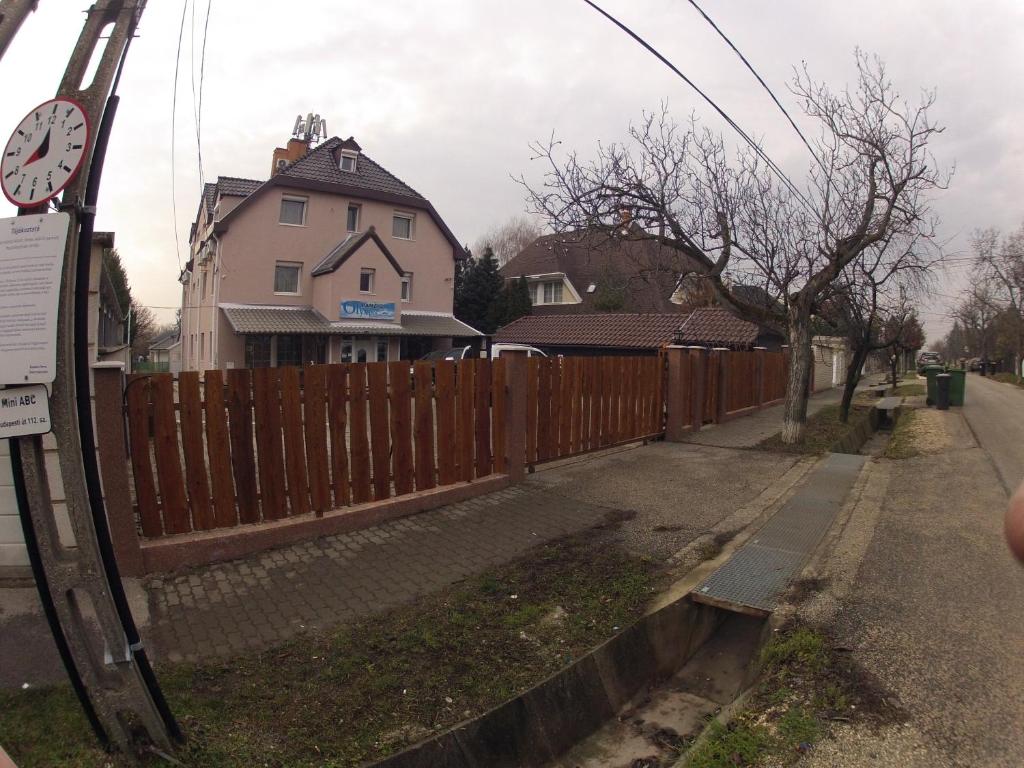 una valla de madera frente a una casa en Olympos Panzió, en Budaörs