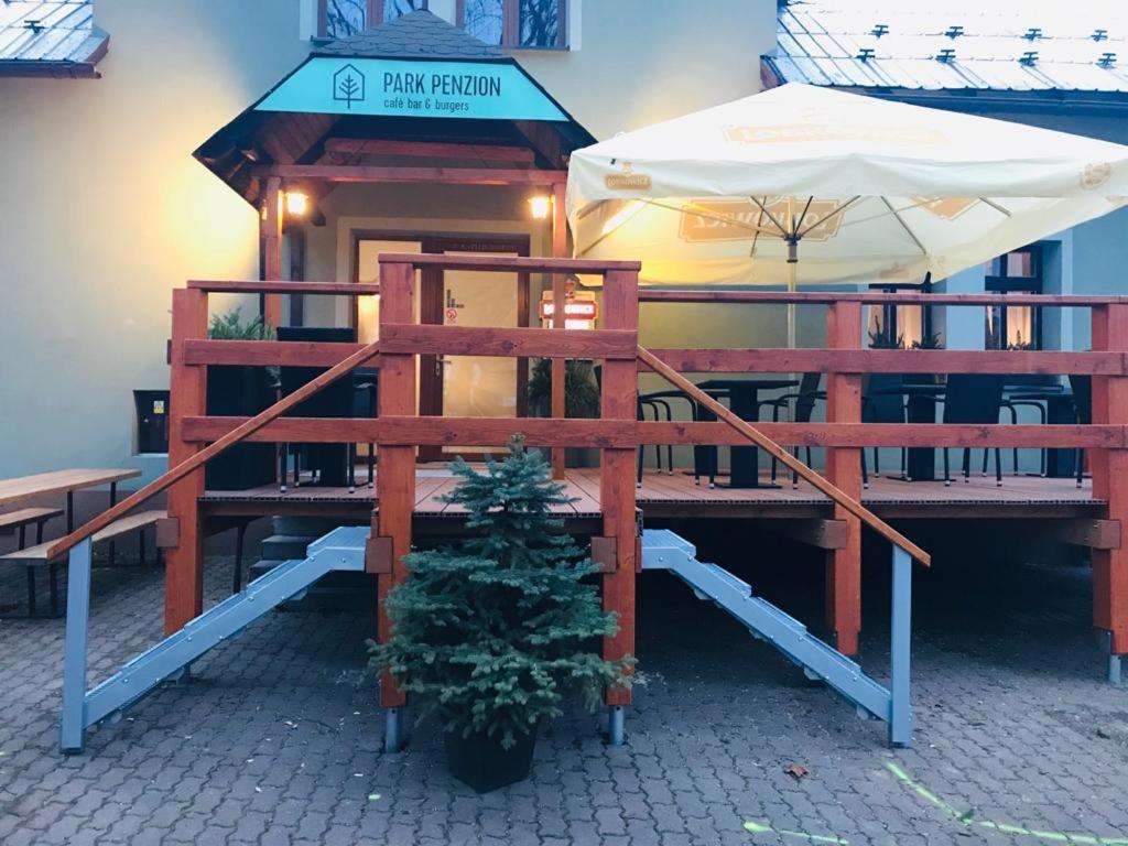 ein Gebäude mit einem Tisch, einem Regenschirm und einem Weihnachtsbaum in der Unterkunft Park Penzion in Malá Morávka