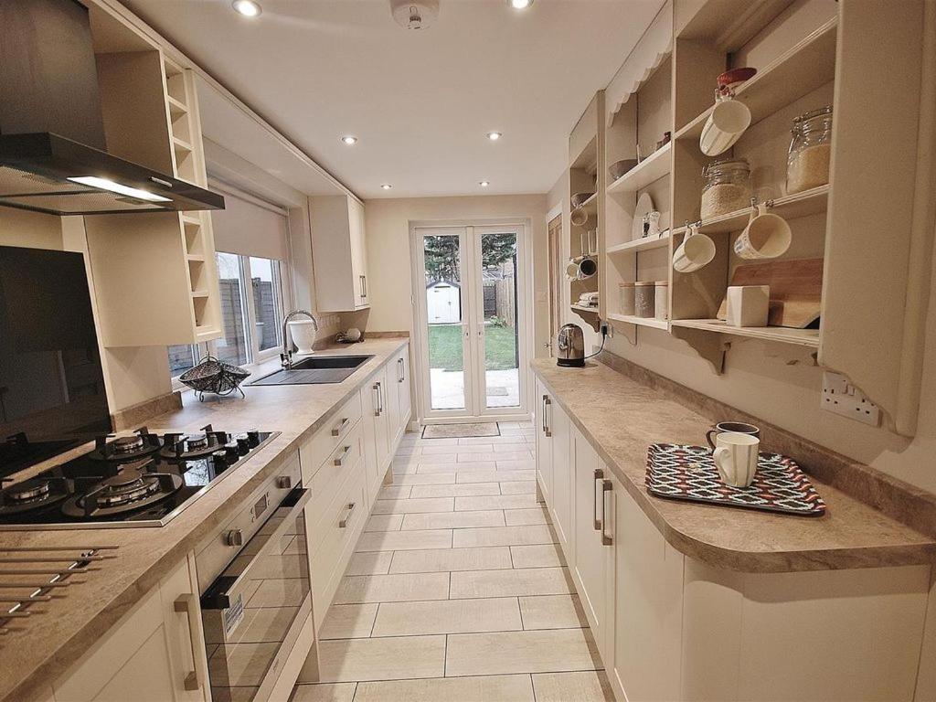 a large kitchen with white cabinets and a stove at EasyRest Spalding - 5 Beds & Free Parking - Central & Quiet Location - 3rd Bedroom Optional - Entire Spacious House in Spalding