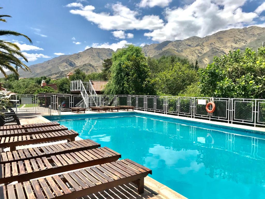 a swimming pool with benches and mountains in the background at Hostería Lida in Merlo