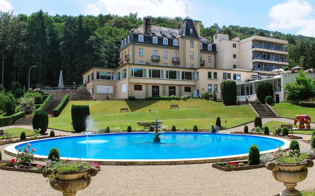 ein großes Haus mit einem großen Pool davor in der Unterkunft Hotel Bel Air Sport & Wellness in Echternach
