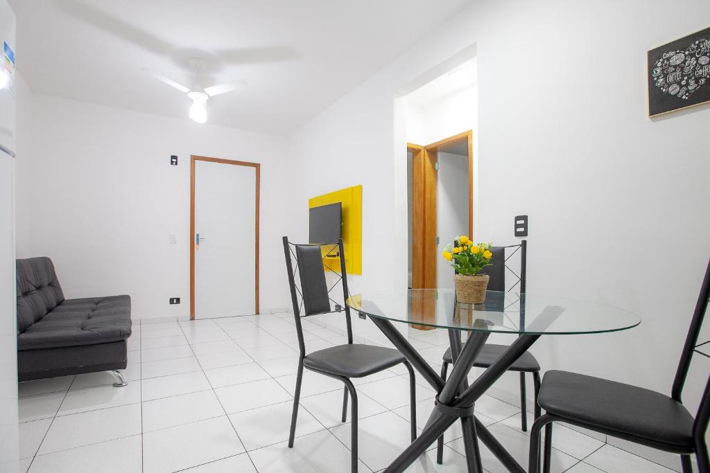 a dining room with a glass table and chairs at Apto Ubatuba Condomínio Sun Way Piscina Churrasqueira in Ubatuba
