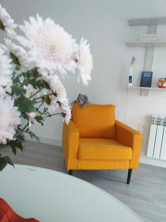 a yellow chair in a living room with flowers at Rusalika in Rivne