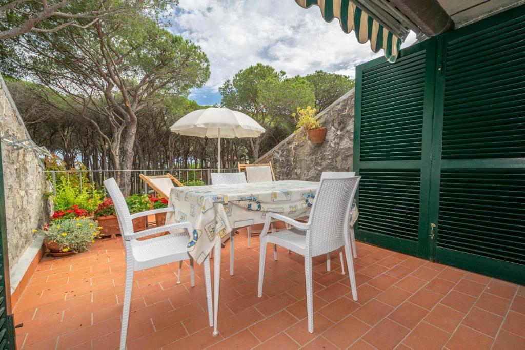 a patio with a table and chairs and an umbrella at Condominio Dunelba in Marina di Campo