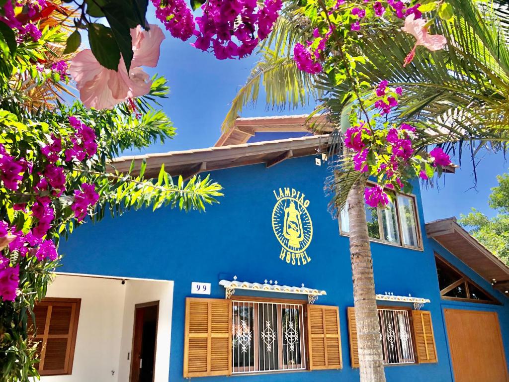 a blue building with a palm tree and flowers at Lampião Hostel in Florianópolis