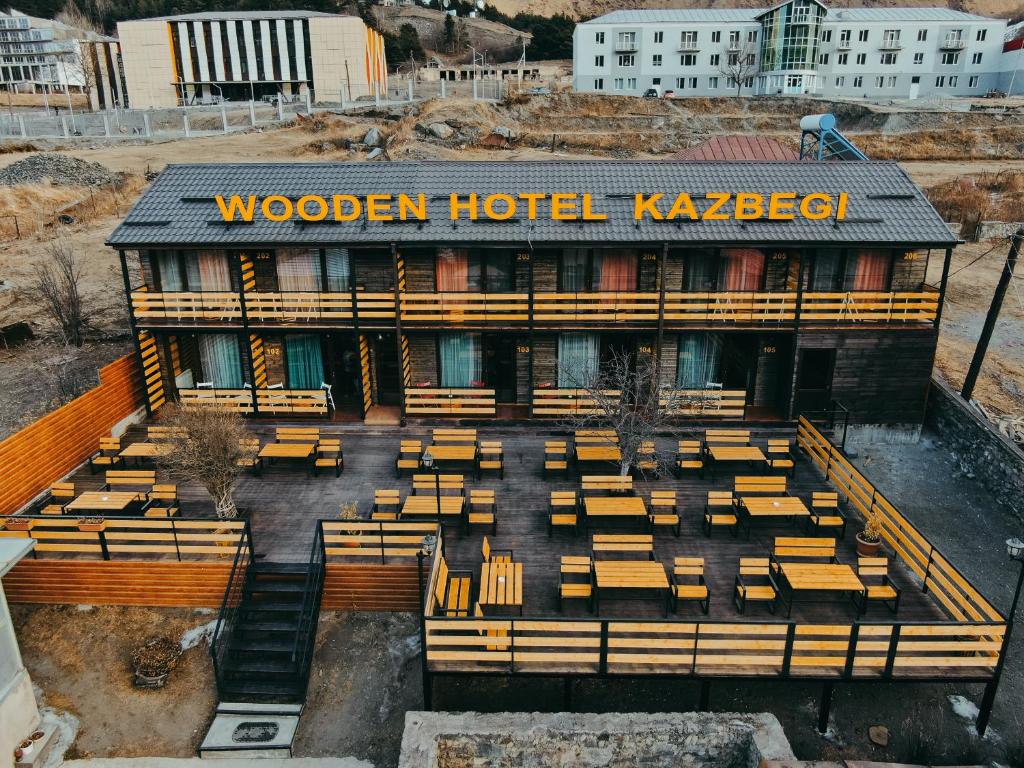 un hotel de madera kazbegi con bancos frente a él en Wooden Hotel Kazbegi, en Kazbegi