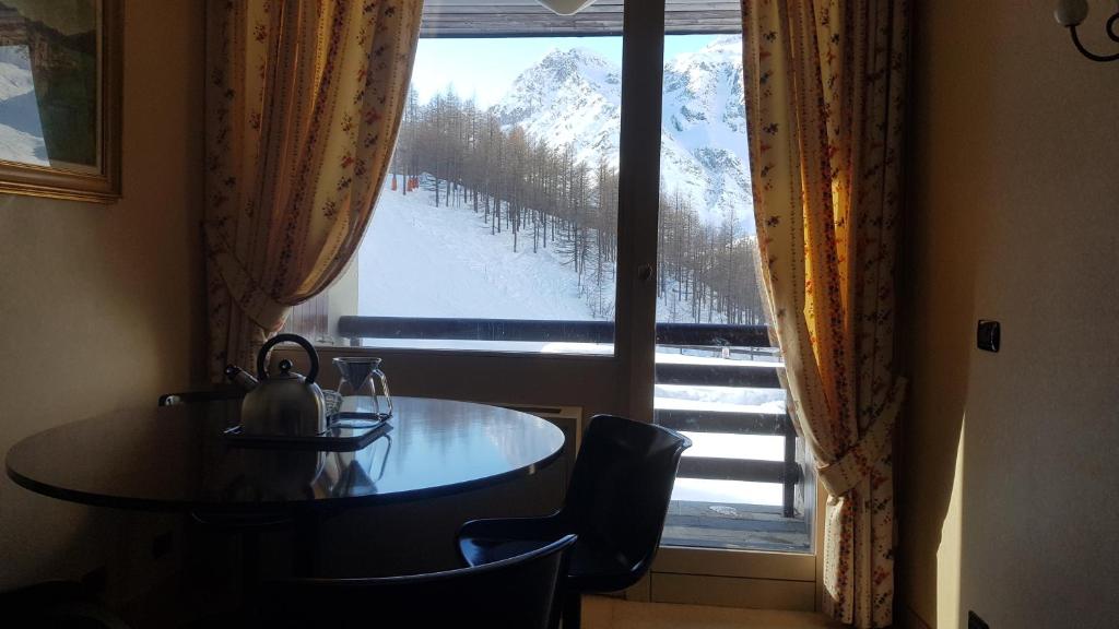 a table and chairs in a room with a large window at Casa Preziosa - Cielo Alto in Breuil-Cervinia