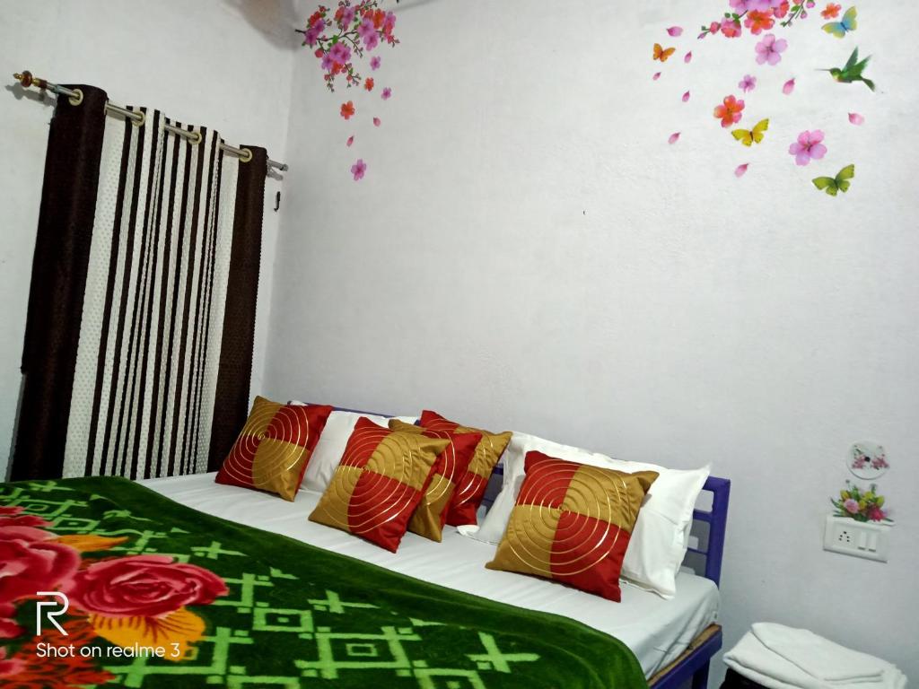 a bedroom with a bed with colorful pillows and flowers at Khajuraho Dreams Homestay in Khajurāho
