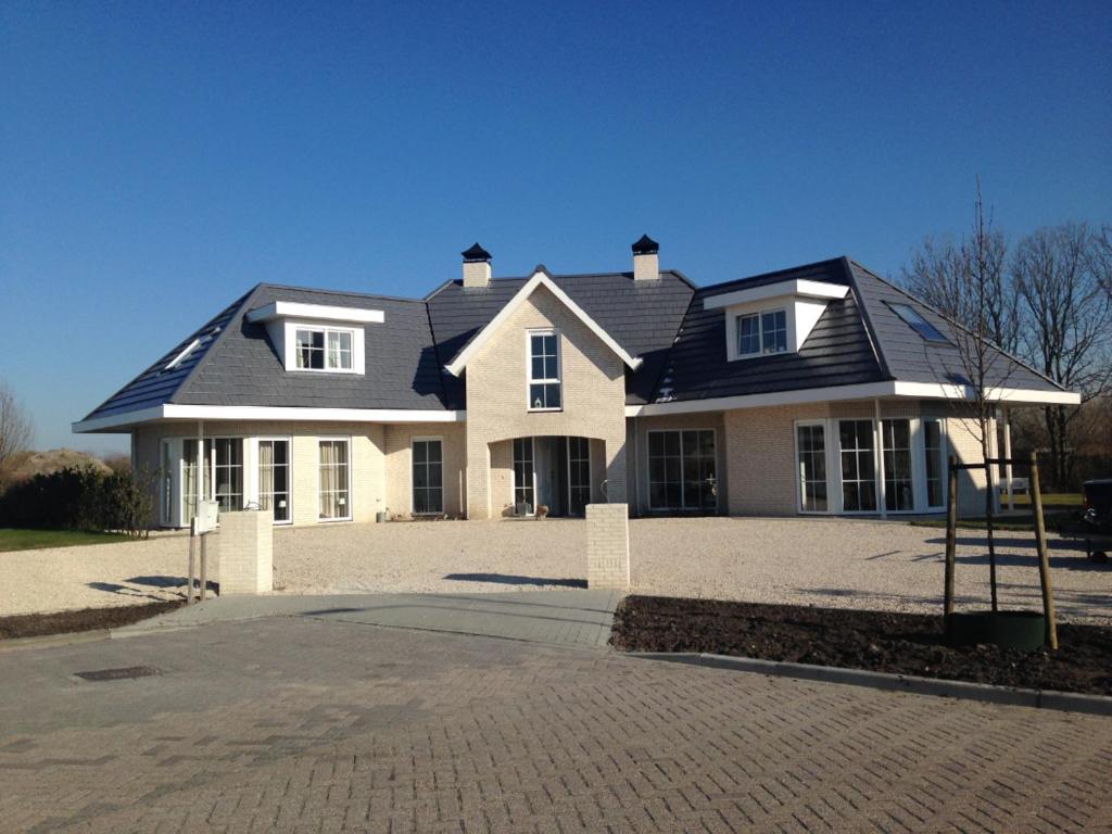 ein großes weißes Haus mit schwarzem Dach in der Unterkunft Luxe prive-kamer - studio in villa aan zee, Dishoek, vernieuwd in Dishoek