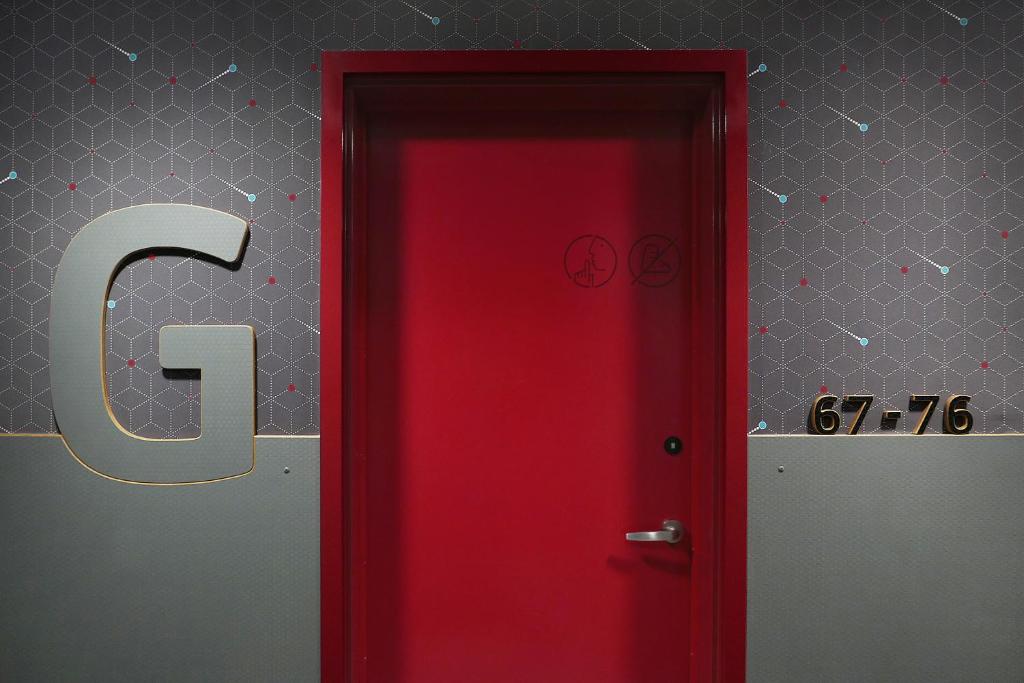 a red door with the letter c on a wall at Pangea Pod Hotel in Whistler
