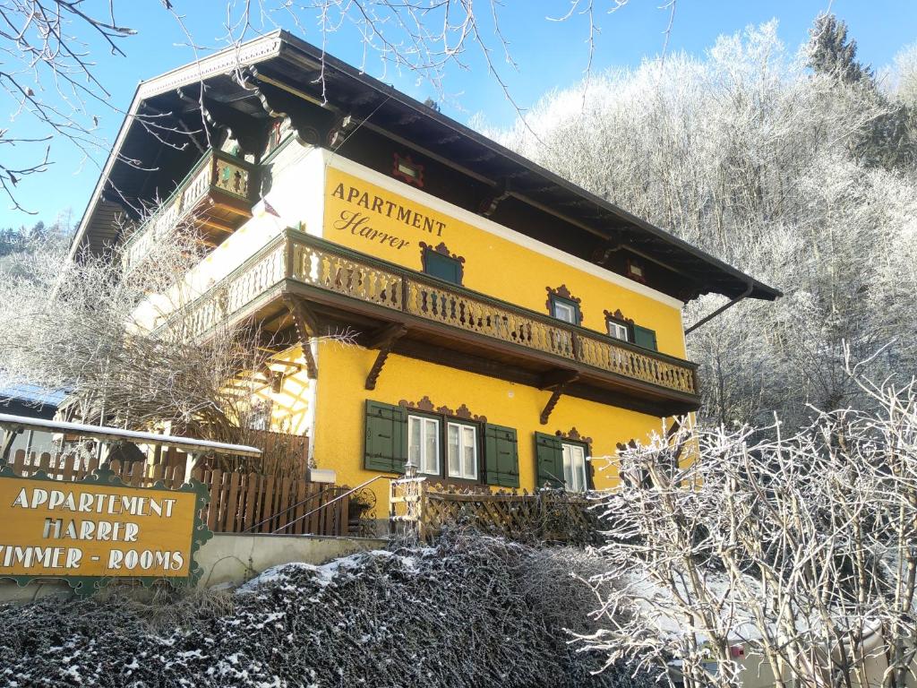 a yellow house with a balcony in the snow at Appartement Harrer in Zell am See