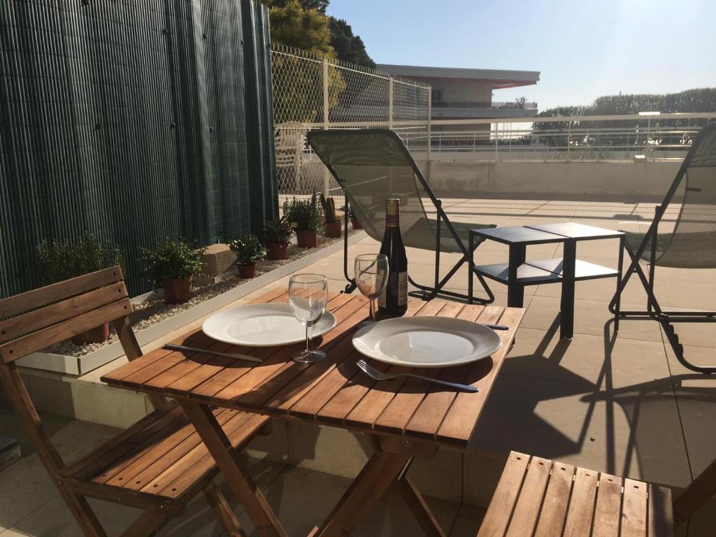 - une table en bois avec 2 verres et une bouteille de vin dans l'établissement Bord de mer, studio avec terrasse, à Villeneuve-Loubet