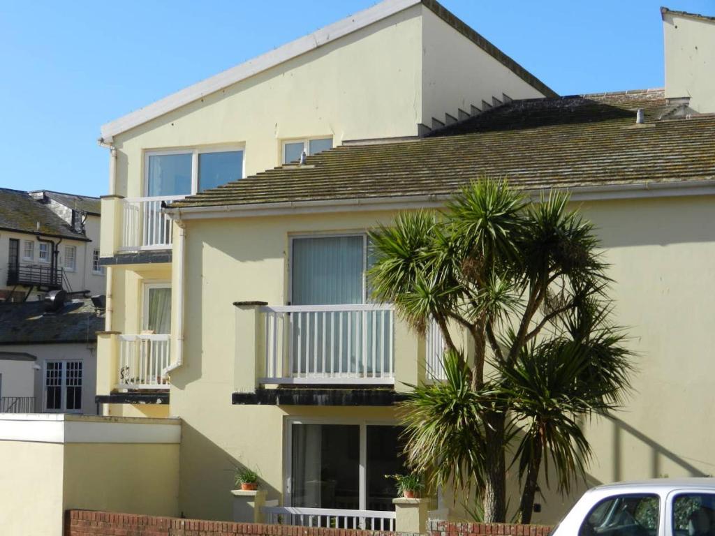 uma casa com uma varanda e uma palmeira em Ocean em Sidmouth
