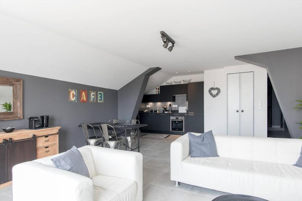 ein Wohnzimmer mit 2 weißen Sofas und einer Küche in der Unterkunft Appartement 4 étoiles vue mer et bord de plage Chez Odette in Saint-Malo