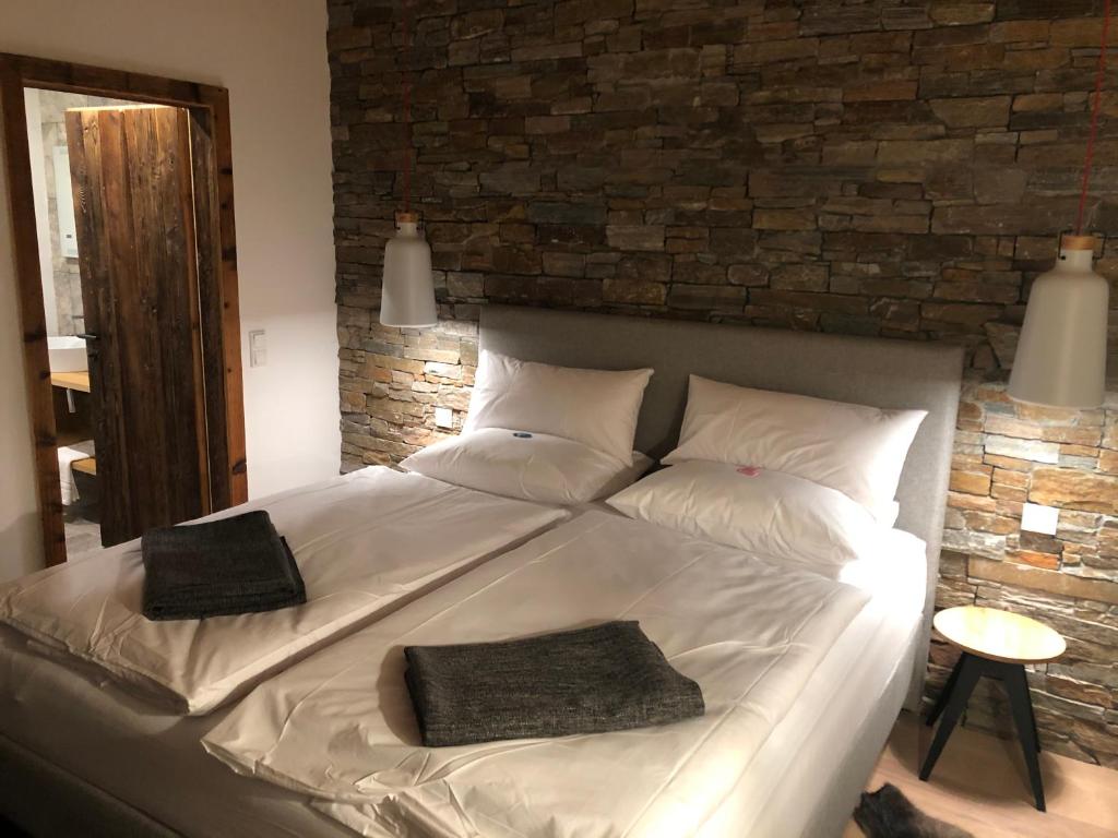1 cama blanca grande con 2 almohadas y pared de ladrillo en Seeapartment am Hallstätter See, en Hallstatt